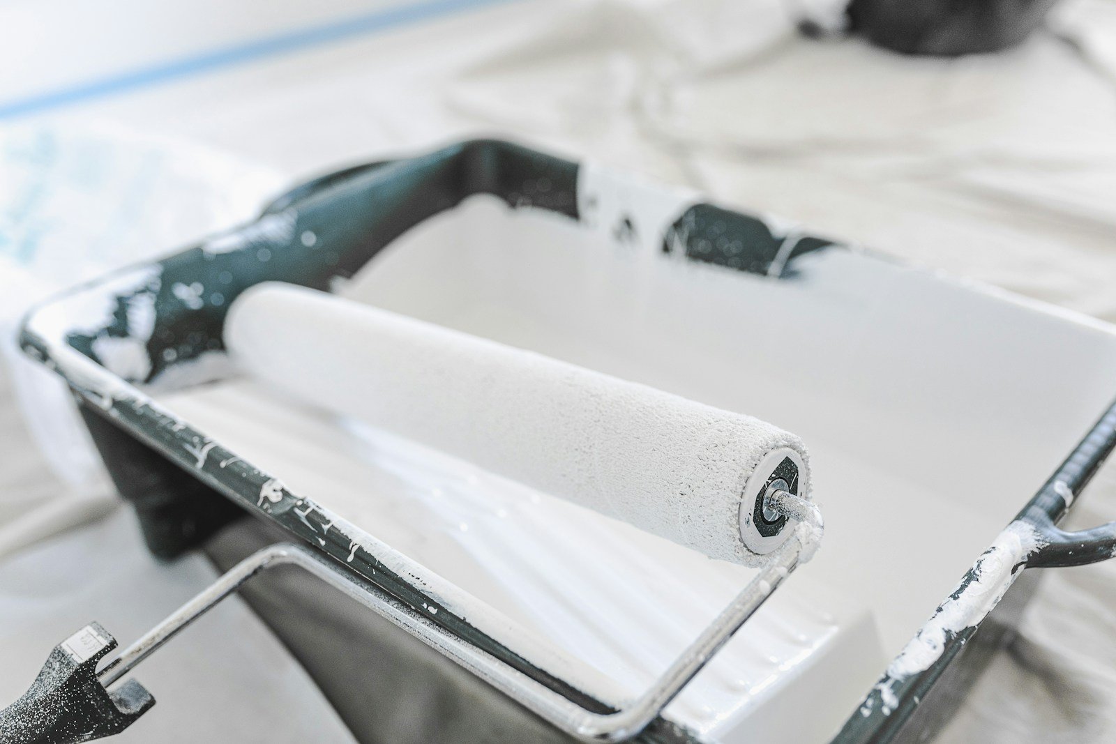 Paint roller and tray filled with white paint